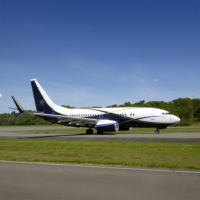 Boeing business jet flying against dark blue sky with clouds